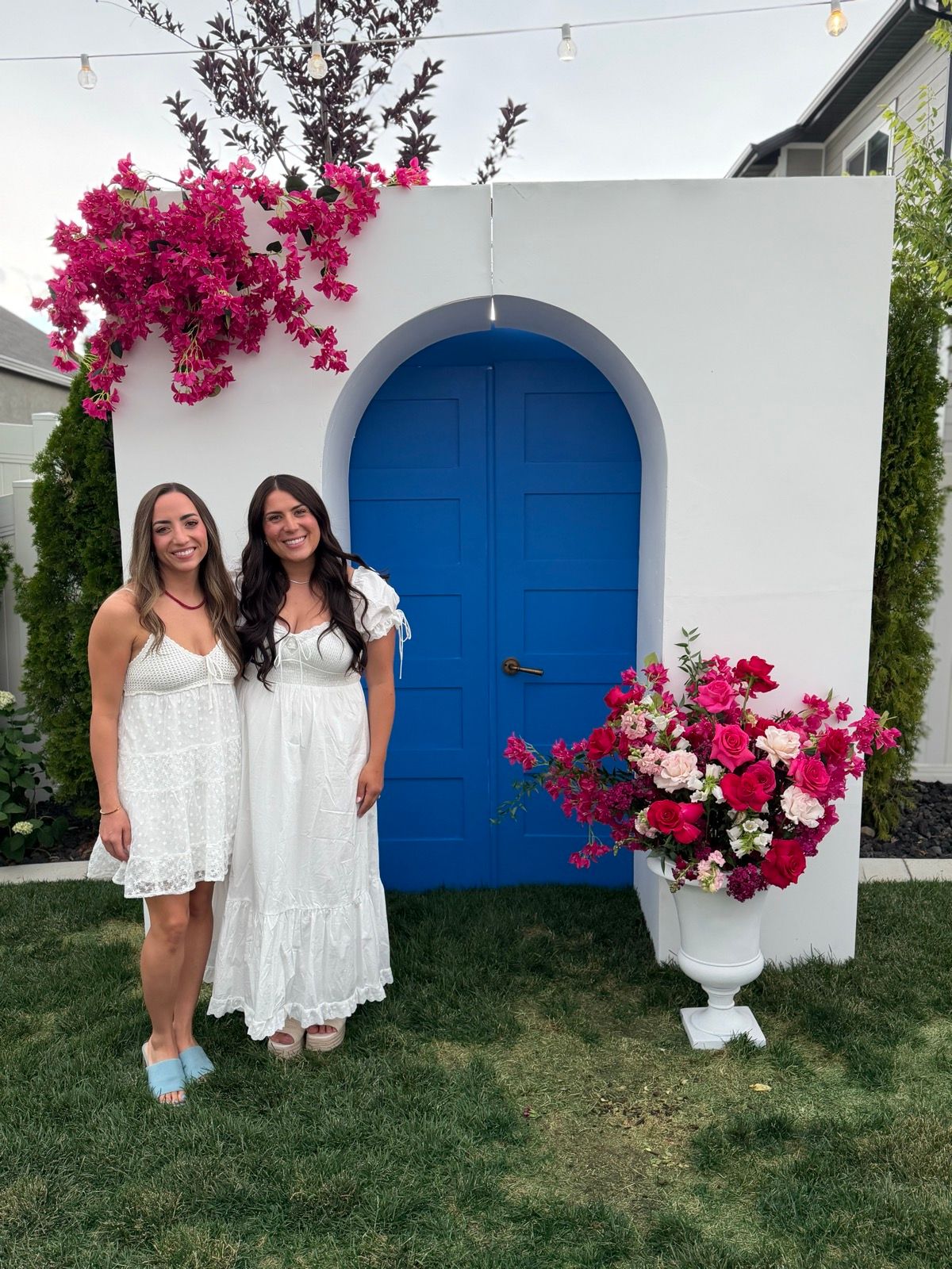 Jordan and Madison together beside a blue doorway and pink flowers