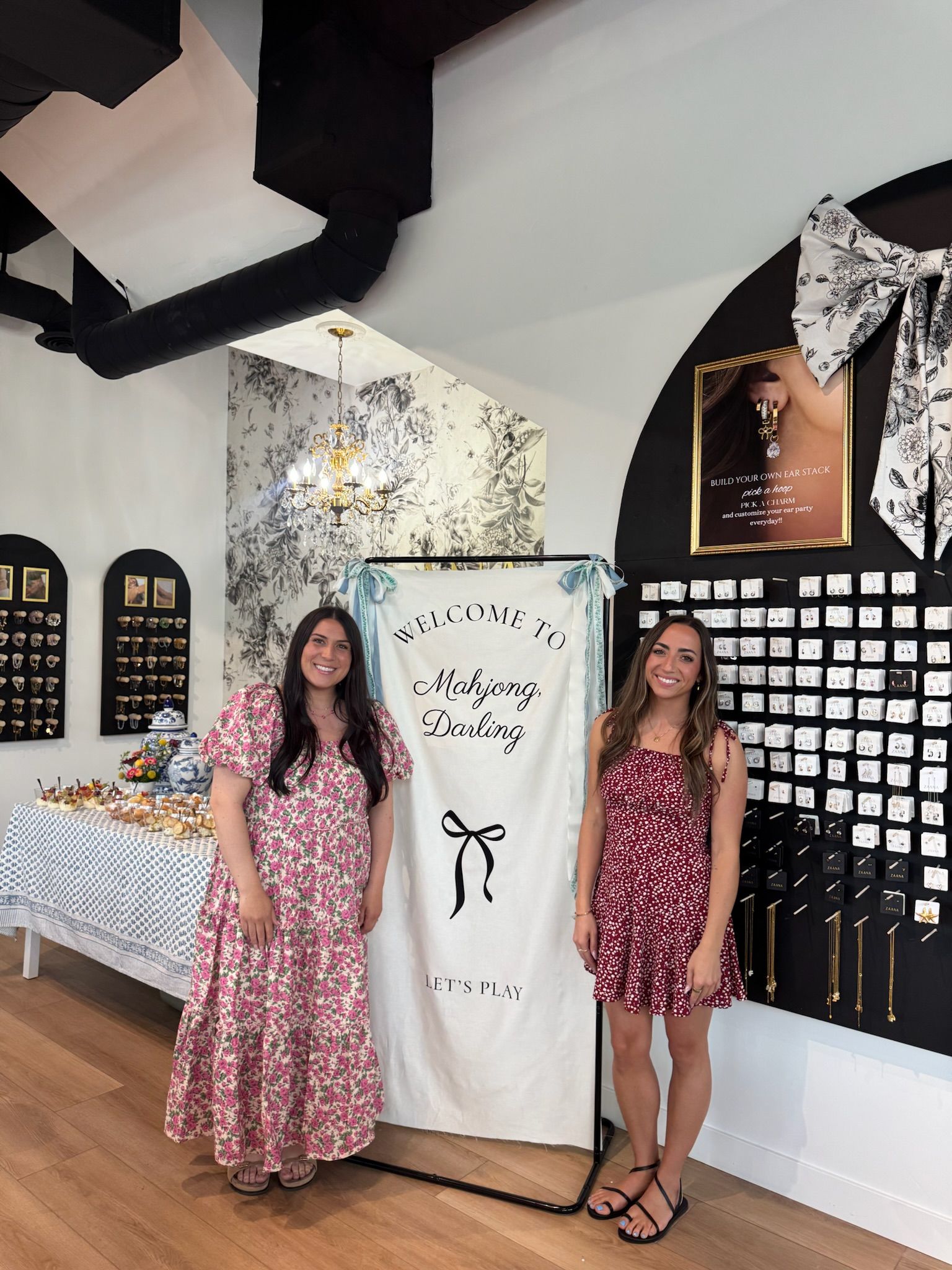 Jordan and Madison beside the Mahjong Darling welcome banner, with Madison in a red floral dress