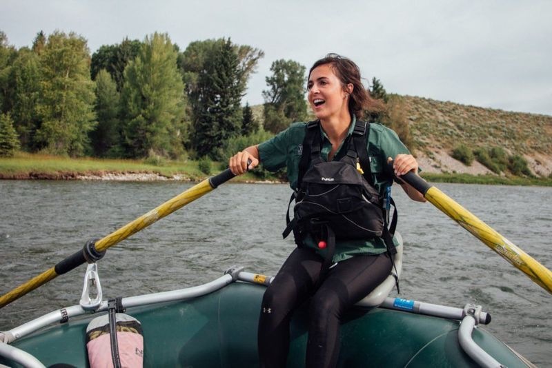 A smiling person at the oars on a calm stretch of river, from the camp archive