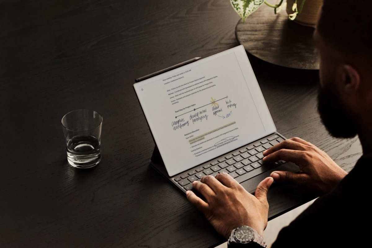 A close-up of a person's hands typing on the Type Folio keyboard, attached to a reMarkable Paper Pro.