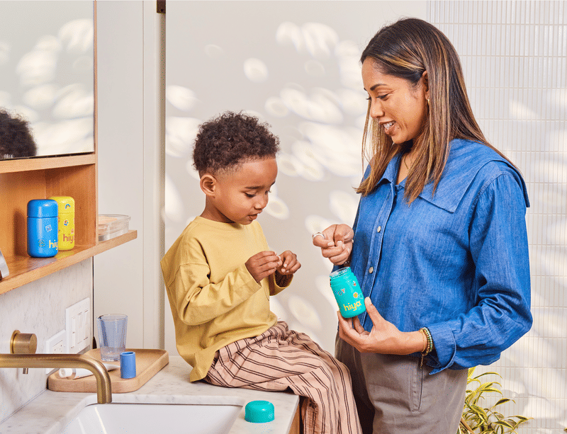 Mom giving her child a Hiya vitamin in a bright bathroom