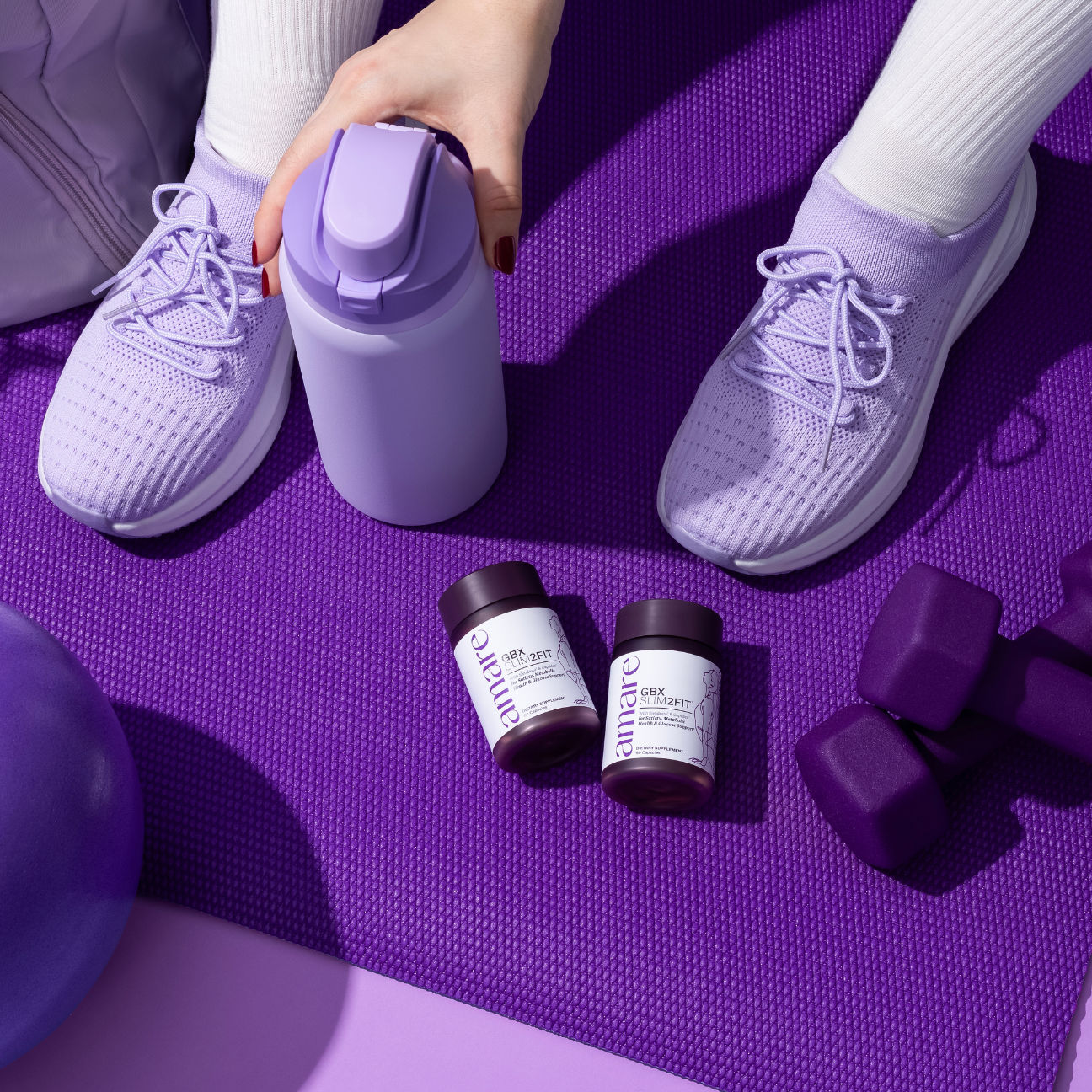 A person in purple sneakers and white socks sits on a purple exercise mat. Nearby are a purple water bottle, two supplement bottles, dumbbells, and a stability ball, creating a cohesive fitness theme.