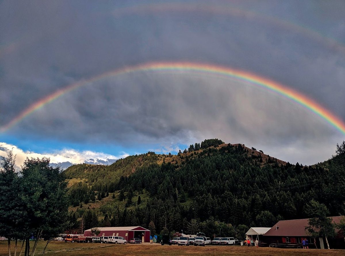 A full rainbow arching over the camp buildings and the hillside