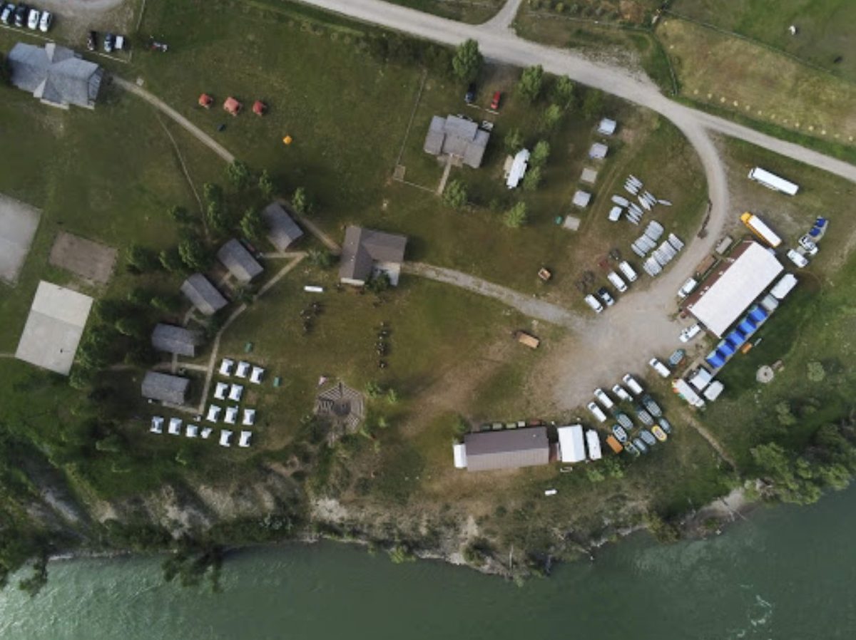 Top-down aerial view of the camp buildings and cabins above the river