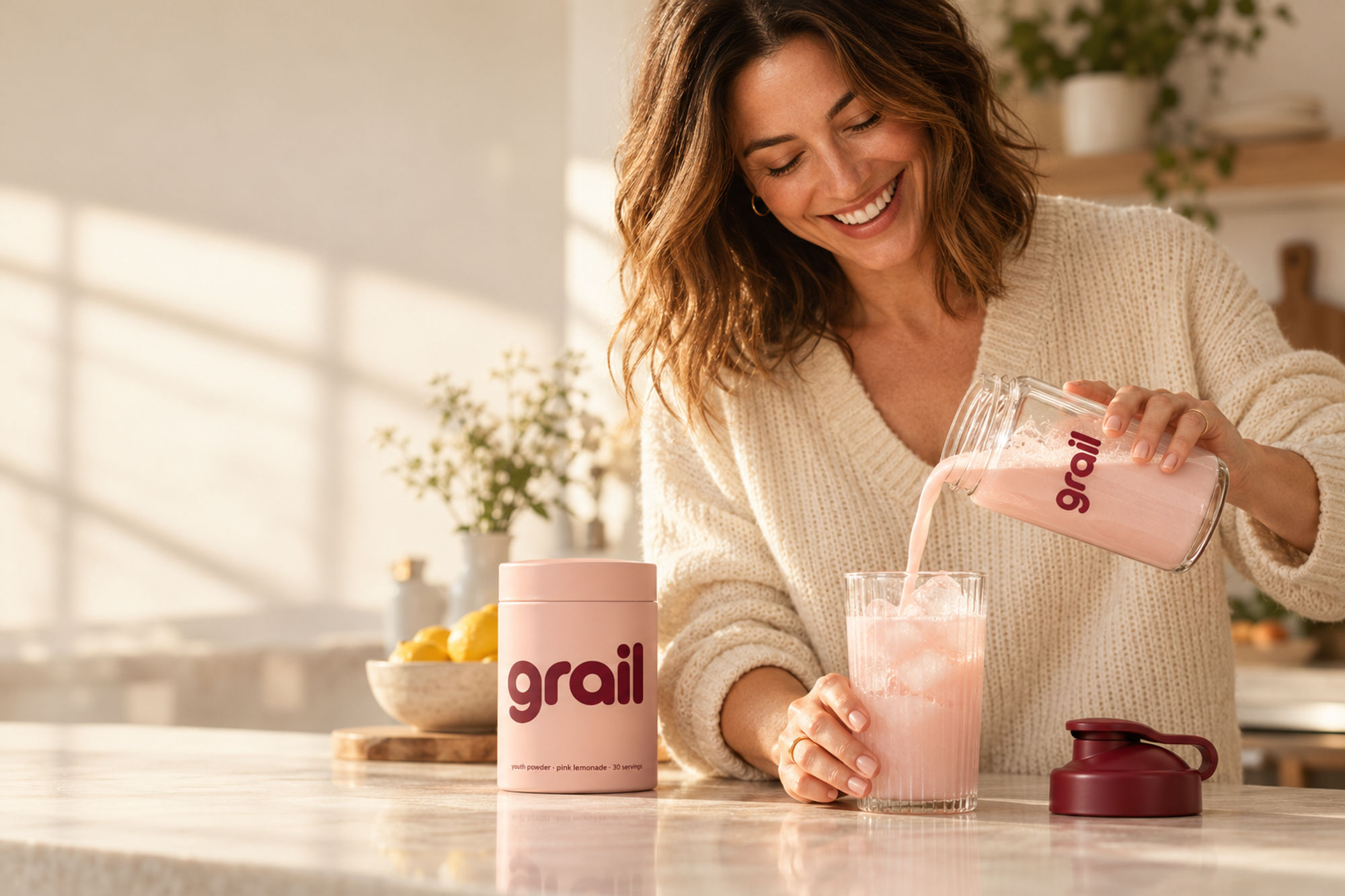 A woman pouring a pink Youth Powder drink in a sunny kitchen
