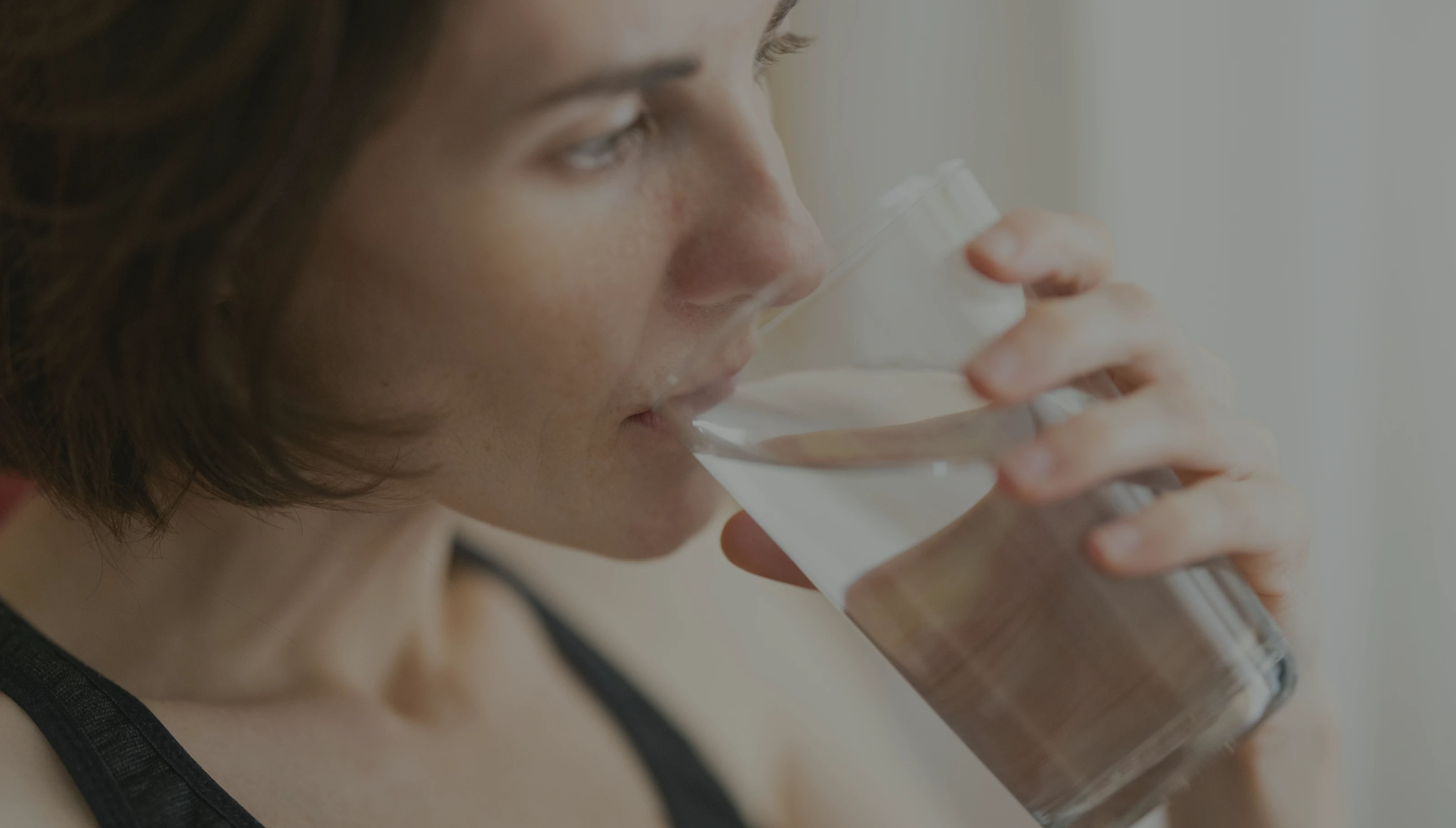 A woman drinking from a glass of water.