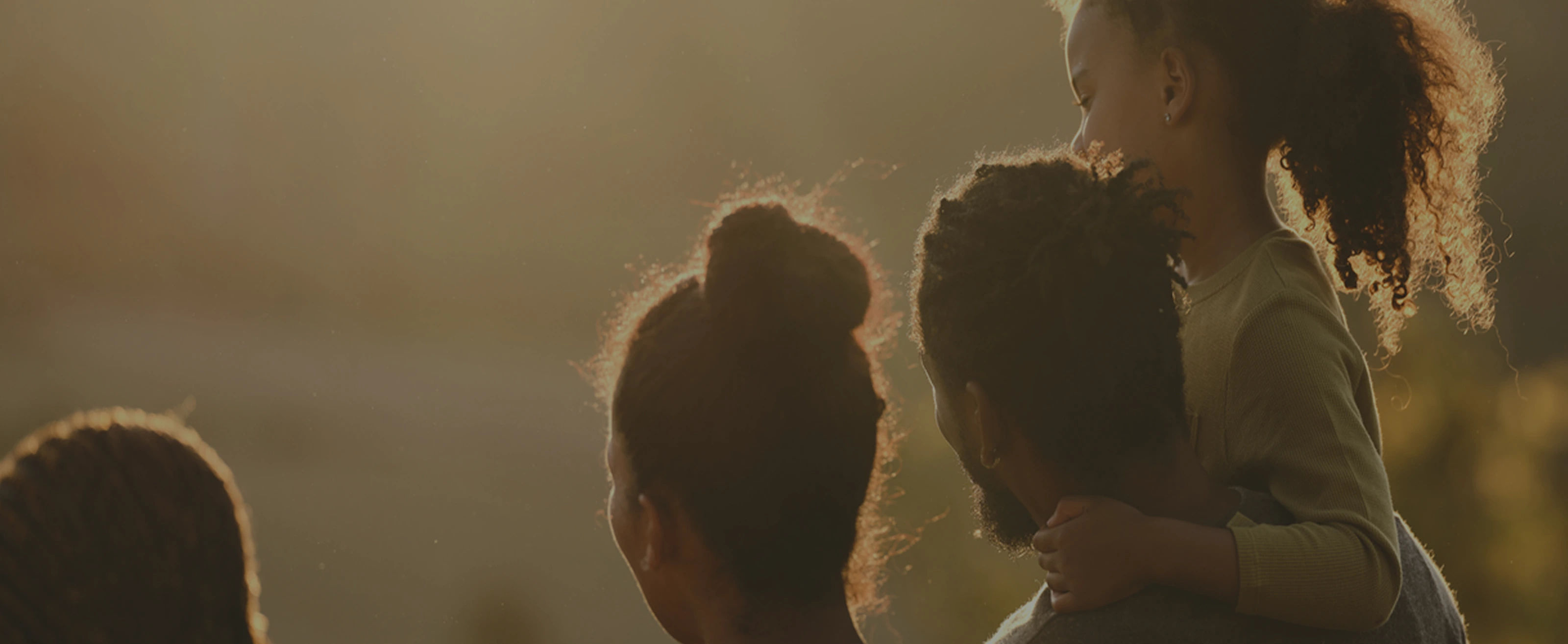 A group of people captured in silhouette during golden hour, creating a warm backlit effect
