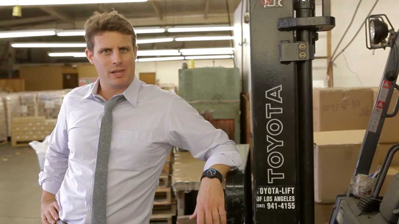 Michael Dubin, in a shirt and tie, leaning on a forklift in the Dollar Shave Club warehouse — the opening shot of the 2012 launch video