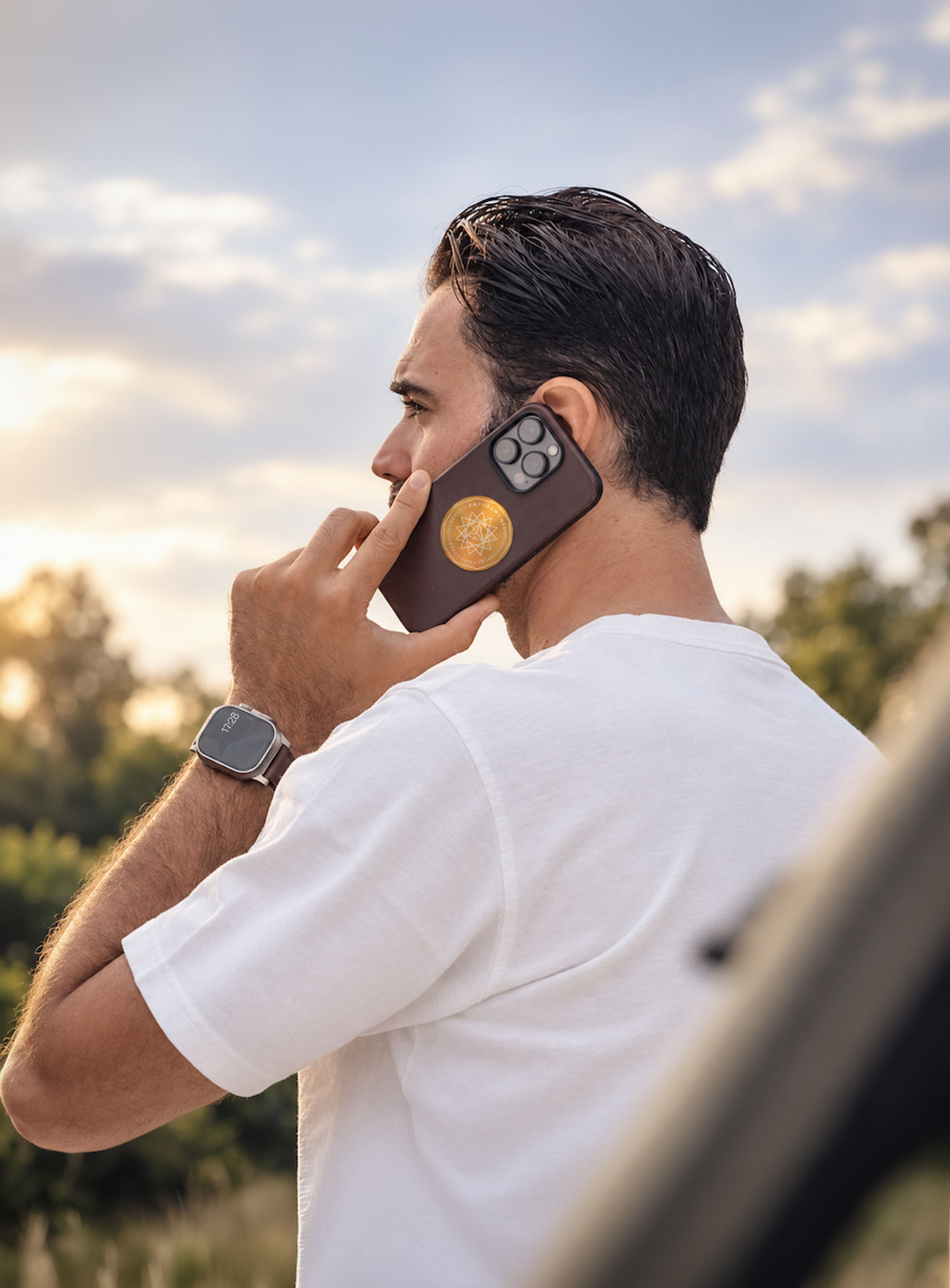 A man on a phone call outdoors at sunset