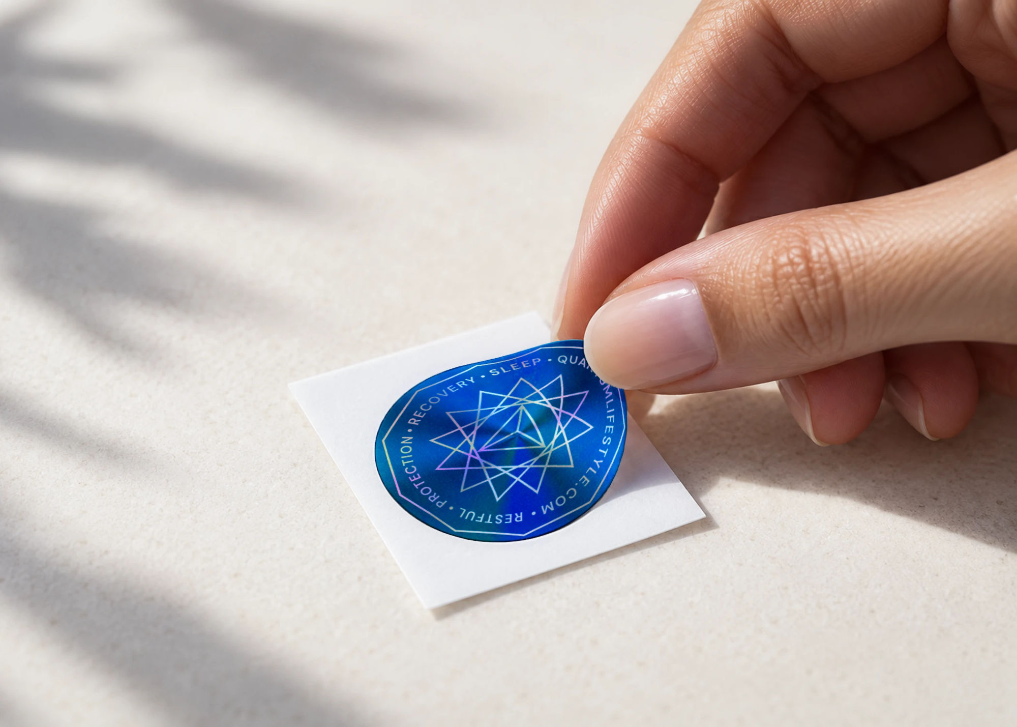 Fingers peeling a blue QuantaGram from its backing sheet