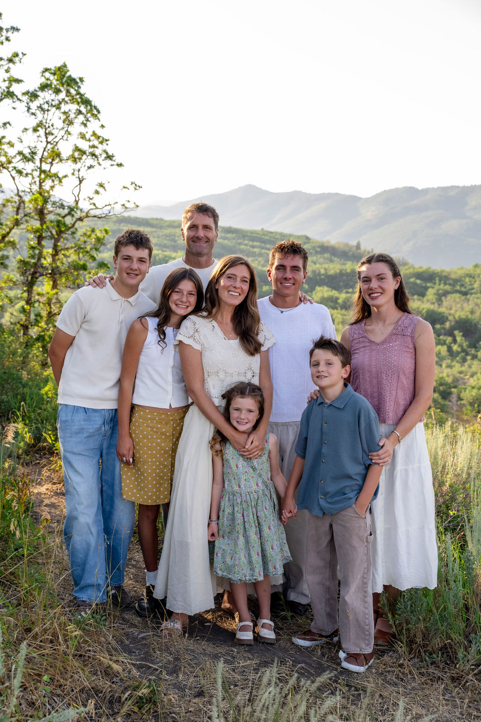 Family standing together among trees and meadow grasses.