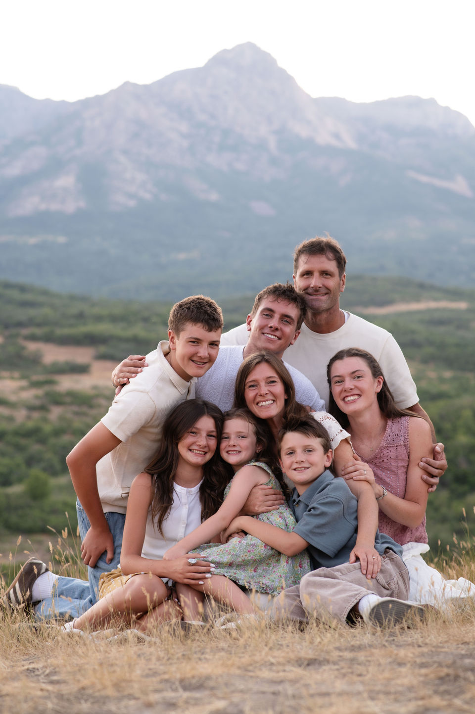 Family seated together in a meadow with mountains behind them.