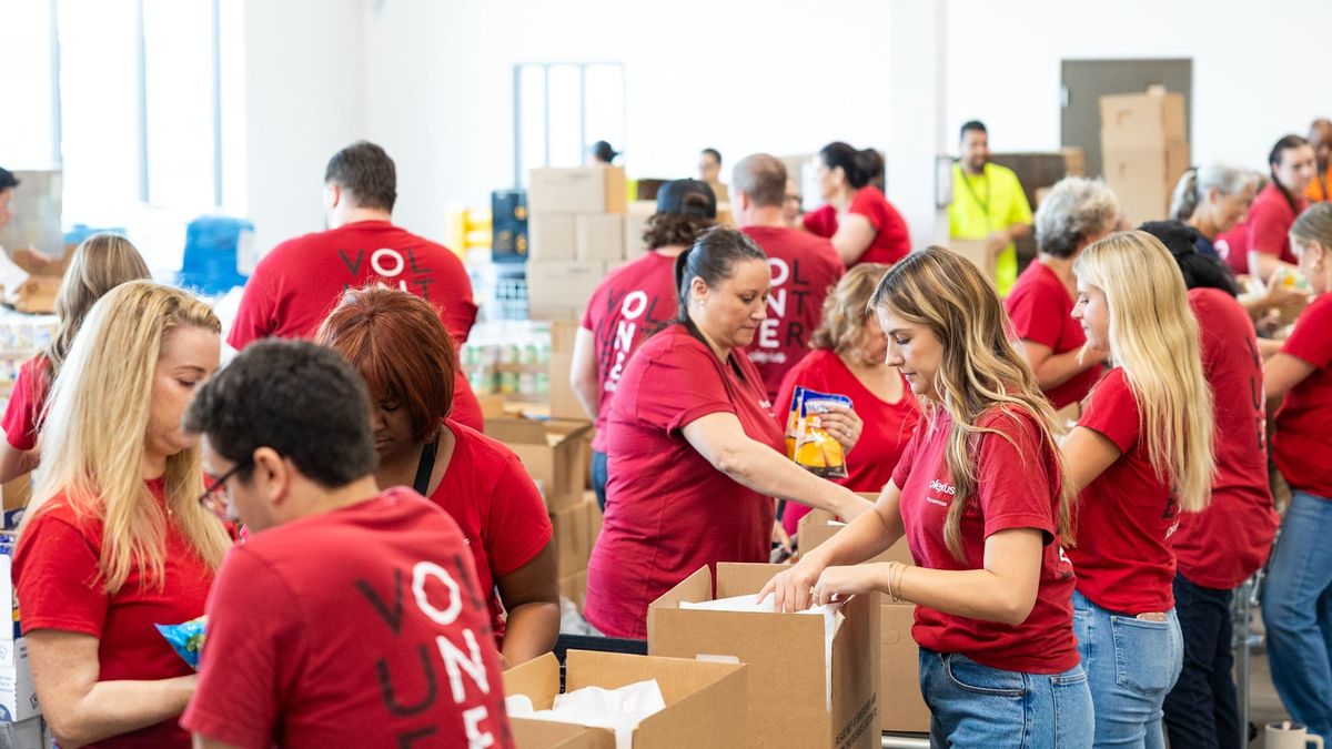 Volunteers in red Plexus shirts packing boxes of food at a community center.