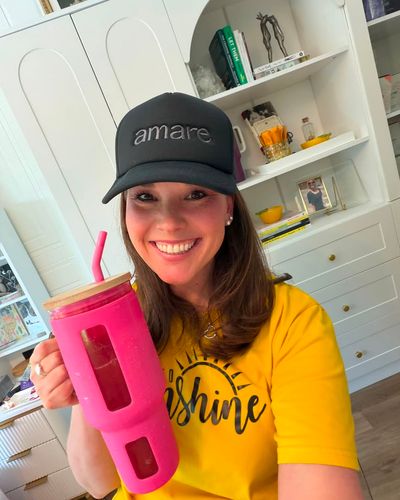Amare community member in an Amare cap holding a tumbler