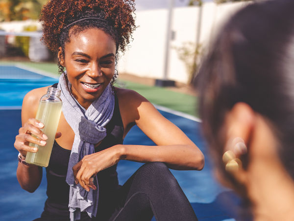 A woman smiling outdoors in the sun.