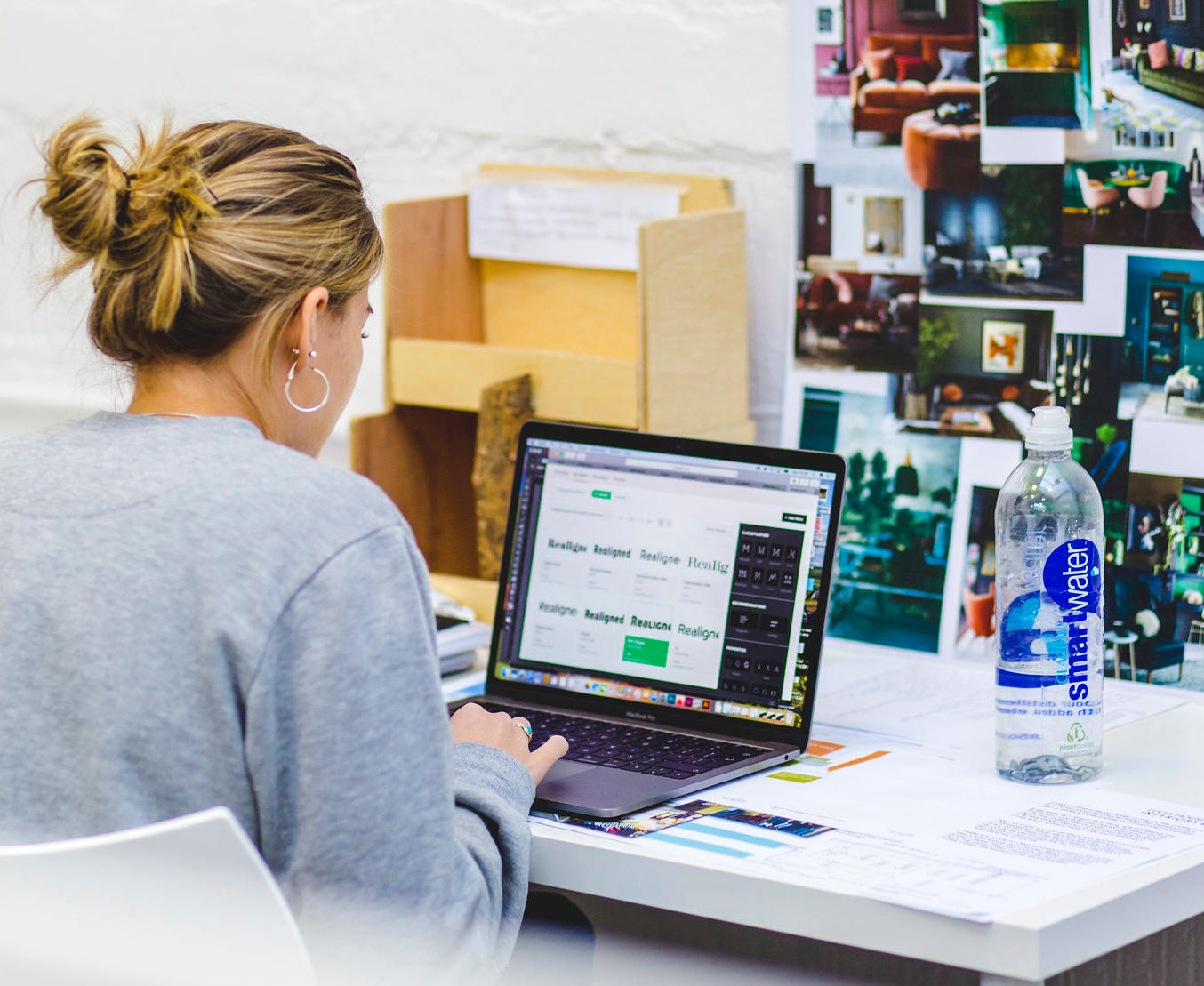 A female Distance Learning student wearing a grey jumper sat at computer at their desk