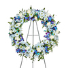 Blue Remembrance Wreath holds White Carnations, Dendrobium Orchids and Blue Daisies