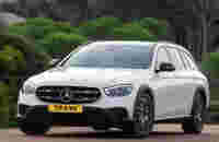 A white Mercedes-Benz car with a sleek design parked on a road surrounded by greenery.