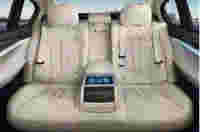 Luxurious beige leather back seats of a car, featuring a central console with a touchscreen display.