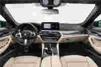 Luxurious BMW car interior featuring beige leather seats, a digital dashboard, steering wheel with controls, and a sleek design.