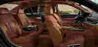 Luxurious car interior with tan leather seats, spacious layout, and modern dashboard, set against a scenic backdrop.