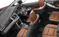 Interior view of a modern vehicle featuring brown leather seats, dashboard controls, and a spacious layout.