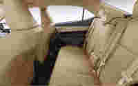 Spacious beige backseat of a car with two headrests and seatbelts, featuring a clean and minimalist design.