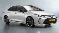 Sleek white Toyota sedan with black alloy wheels, detailed front grille, and shiny surface, set against a gray backdrop.
