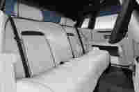 Luxurious rear seating in a car, featuring white leather upholstery, headrests, and a sleek interior design.