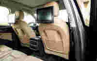 Elegant car interior featuring beige leather seats, backseat entertainment screens, and modern climate controls.
