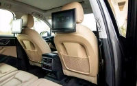 Elegant car interior featuring beige leather seats, backseat entertainment screens, and modern climate controls.