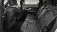 Spacious, modern car interior showing five black leather seats, with a view of greenery through the windows.