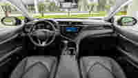 The interior of a Toyota car features a sleek dashboard, touchscreen display, and leather seats, with a view outside.