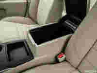 Car interior featuring beige upholstery, a console with an open storage compartment, and cup holder beside it.