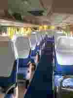 Clean, empty bus interior with blue seats covered in white protective covers and yellow curtains at the windows.