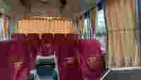 Inside a tour bus with maroon seats and yellow curtains, ready for passengers. The mood is calm and waiting.
