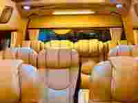 Luxurious van interior with beige leather seats, soft lighting, and curtains, creating a comfortable and classy atmosphere.