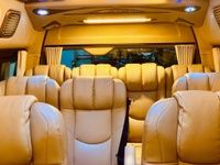 Luxurious van interior with beige leather seats, soft lighting, and curtains, creating a comfortable and classy atmosphere.