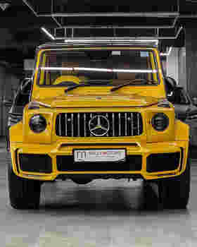Bright yellow Mercedes-Benz G-Class SUV showcased in a modern showroom with sleek lighting and a polished floor.