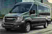 A silver van, labeled "URBANIA," parked near modern glass buildings in an urban setting.