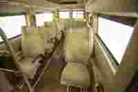 Interior of a vehicle featuring several light-colored, cushioned seats arranged along the sides.