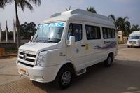 A white Force Traveller van parked on a concrete road, palm trees and construction site visible in the background.