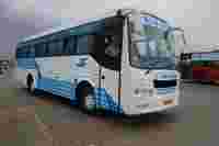 A white and blue public bus with "E.J.A.S" and "SRI MARUTHI" signage parked at a bus station with people nearby.