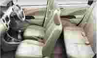 Interior of a car featuring beige leather seats, a steering wheel, and a gear shift, with a minimalist design.