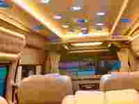 Luxurious van interior featuring plush seating, mood lighting, and a sleek design with sound system controls visible.
