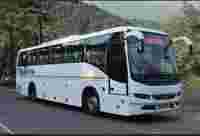 A white Volvo bus labeled "Northern" parked on a scenic road surrounded by trees and mountains.