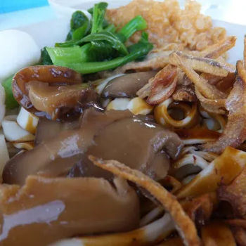 Broad Pan Mee topped with anchovies, sliced mushroom, fried shallot and a bowl of soup with two fish balls, bean curb sheet and veggie