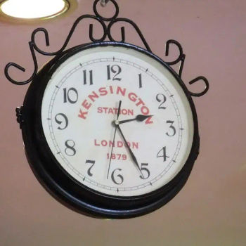 An old antique clock hanging on the ceiling at the shop.