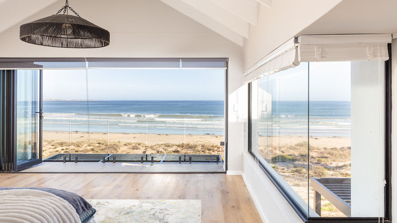Edited photo of a bedroom overlooking the ocean, showing vibrant interior tones and visible ocean view through the windows.
