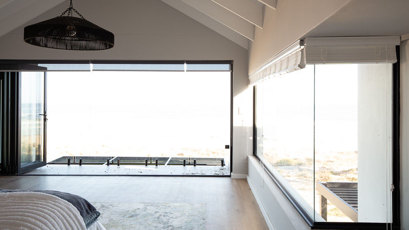 Unedited photo of a bedroom overlooking the ocean, with details outside the window lost due to limited dynamic range.